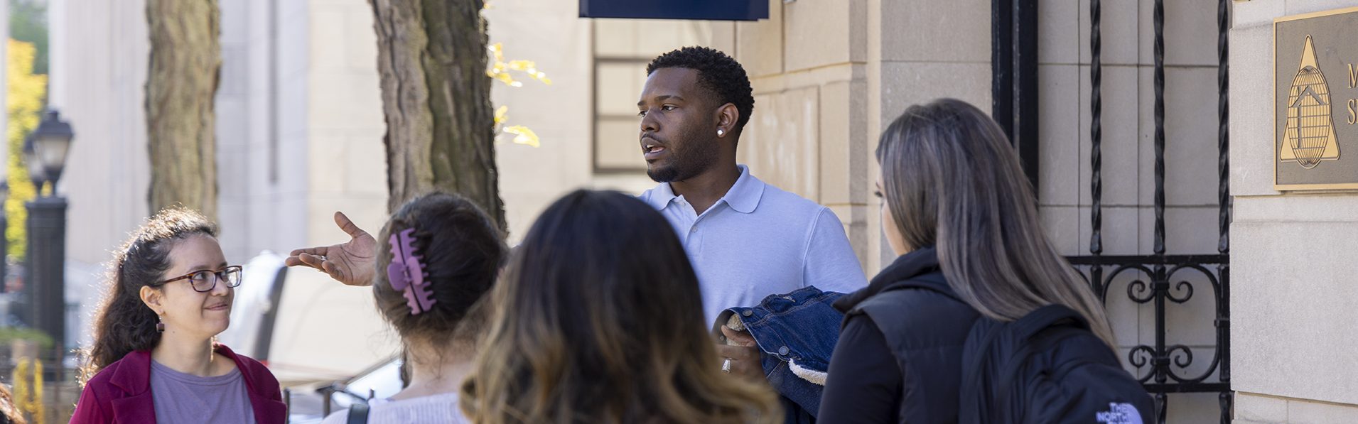 A UConn Waterbury Urban Community Studies student presenting his project to his fellow classmates on site in front of the Nest building in downtown Waterbury